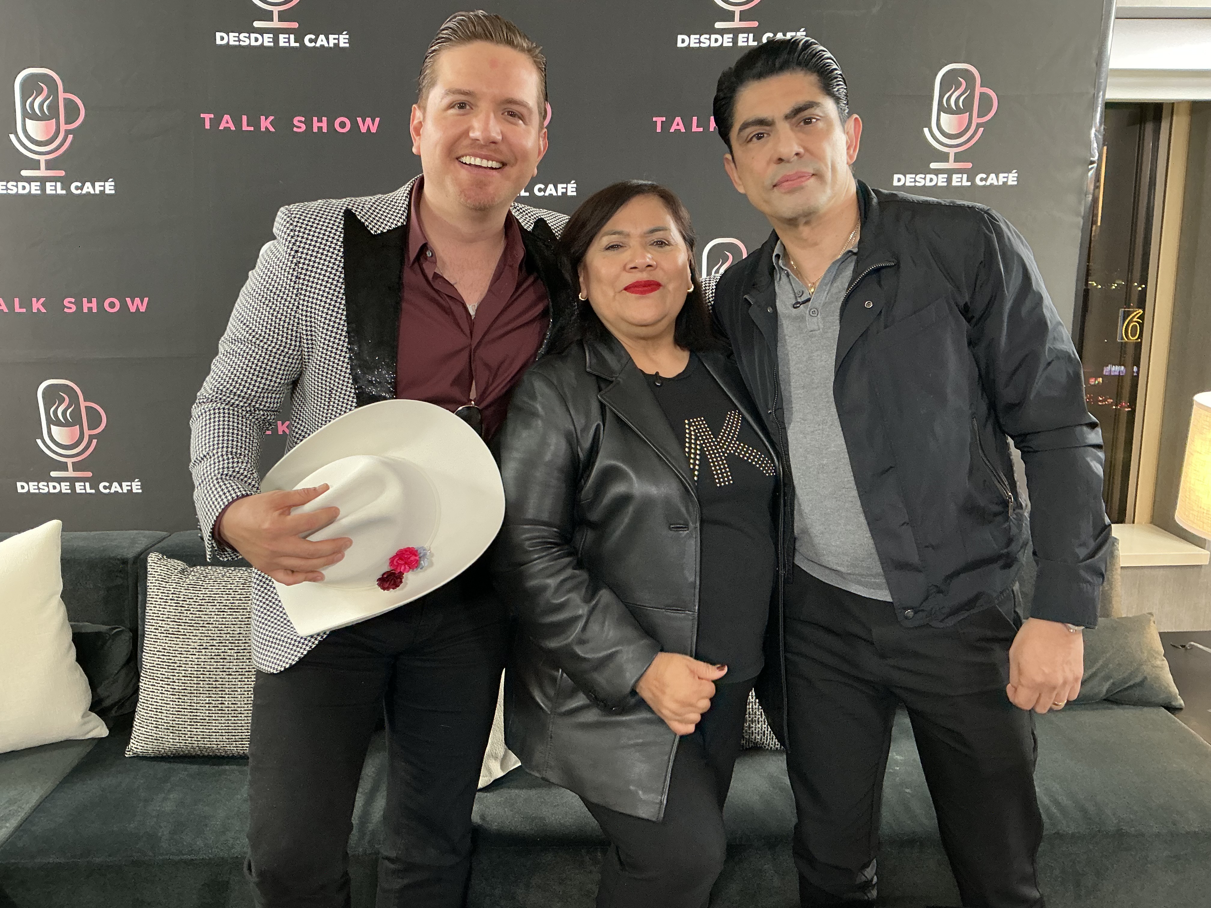 Conductora y invitados de Desde el Café Talk Show frente al muro de prensa